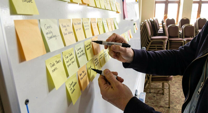 Sticky notes with page names arranged on a whiteboard during a church website planning meeting.